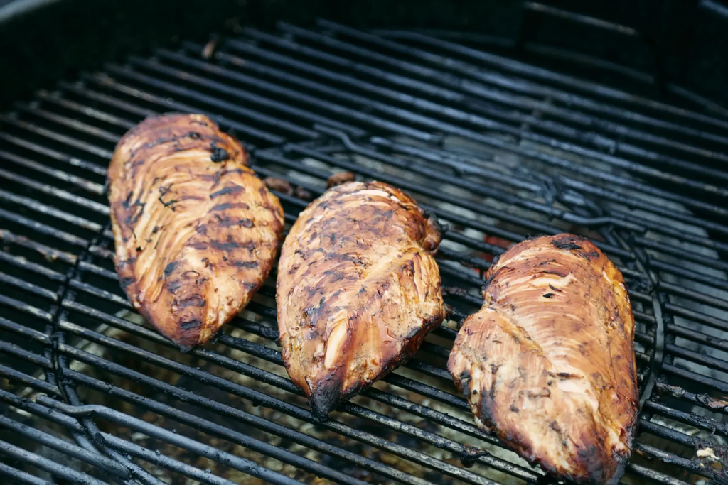焼き網の上に並べられた、焼き目の付いた3枚の鶏肉。
